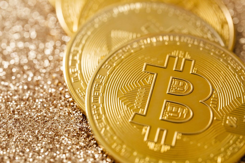 Golden Bitcoin coins on a shimmering glitter surface, symbolizing digital currency and financial innovation.