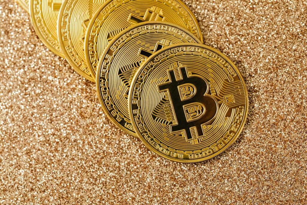 Golden Bitcoin coins arranged on a sparkling glitter surface, symbolizing cryptocurrency and wealth.